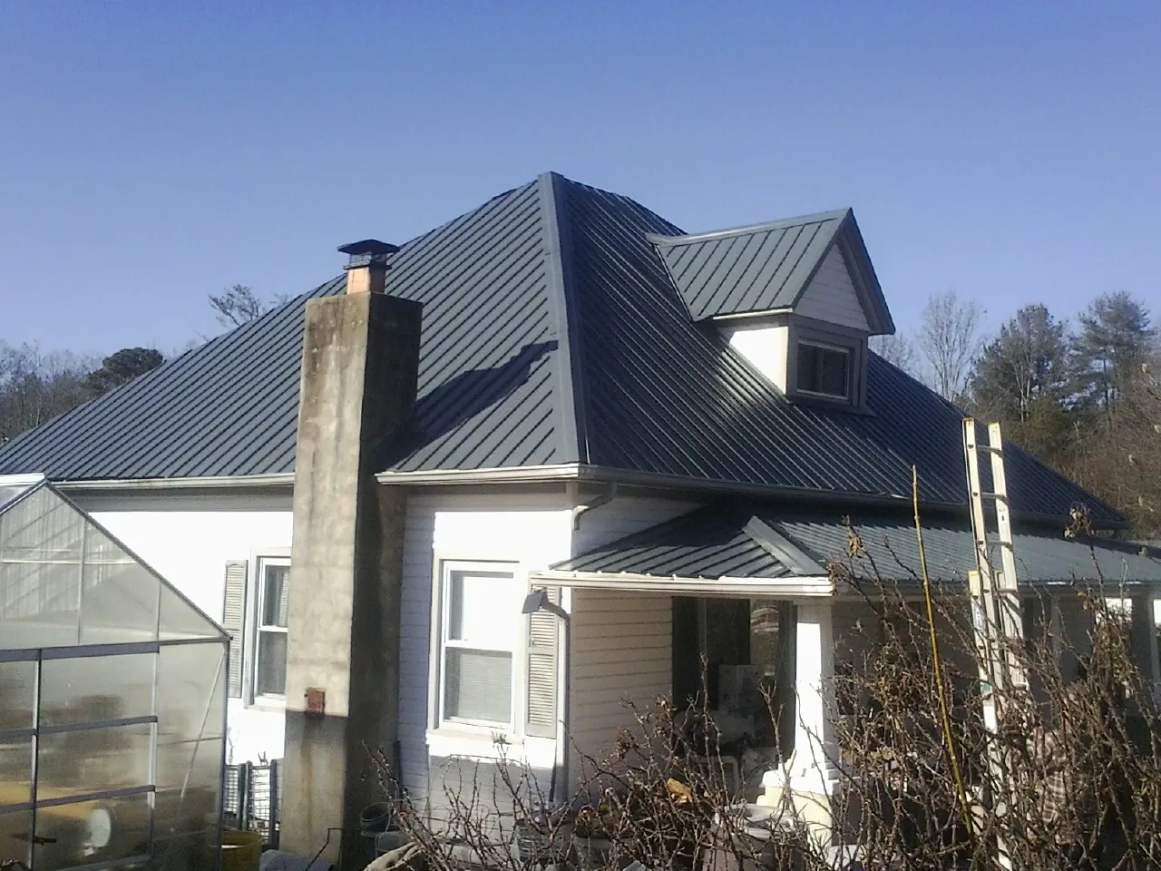 Dark blue standing seam metal roof on a white farmhouse with dormer — Slate & Tile Roof Repair by Roofing Brothers in Westhampton