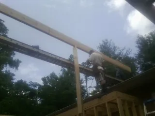 Carpenter setting a ridge beam over a new addition frame — Ice Dam Removal by Roofing Brothers in Westhampton