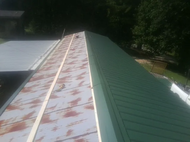 Old rusted panels beside newly installed green metal roofing — Wind Damage Roof Repair by Roofing Brothers in Westhampton