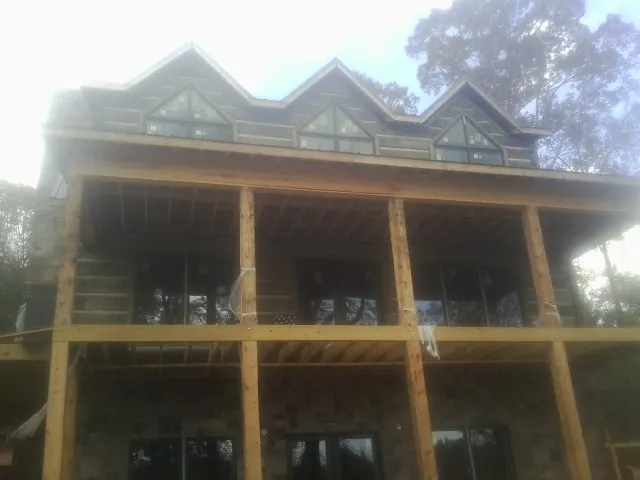 Dormers and porch framing on a large log home under construction — Roof Coating work by our crew in Westhampton