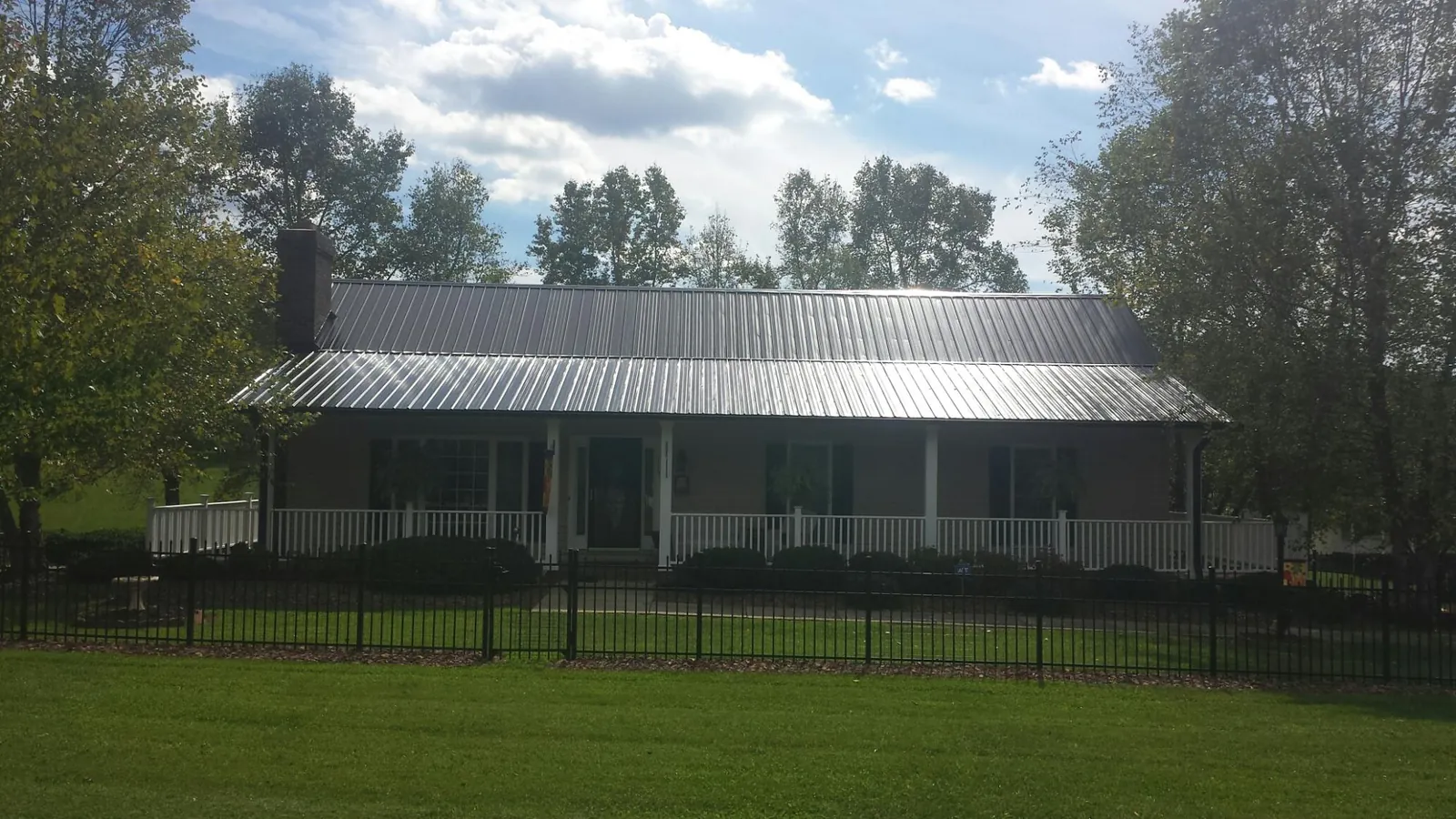 Gray metal roof on a brick ranch with a full width front porch — Gutter Guard Installation work by our crew in Westhampton