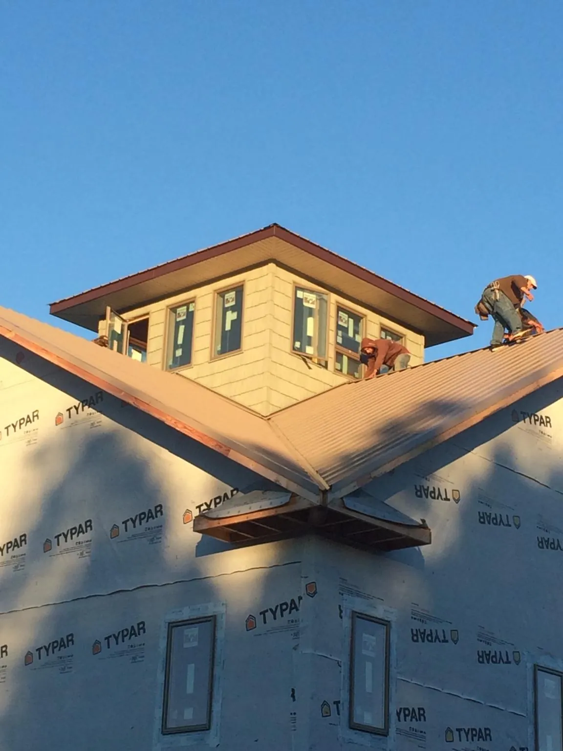 Roofers working around a rooftop cupola on a new metal roof at sunset — Roof Waterproofing in Westhampton by Roofing Brothers